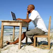 男子在海滩上的办公桌前工作的照片