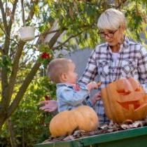 photo of grandmother with toddler working on carving a pumpkin